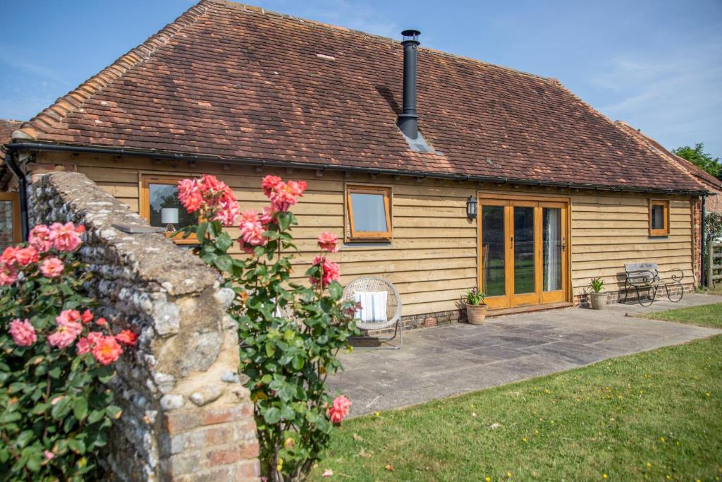 a wooden house with a brick wall and flowers at The Cowshed in Hooe