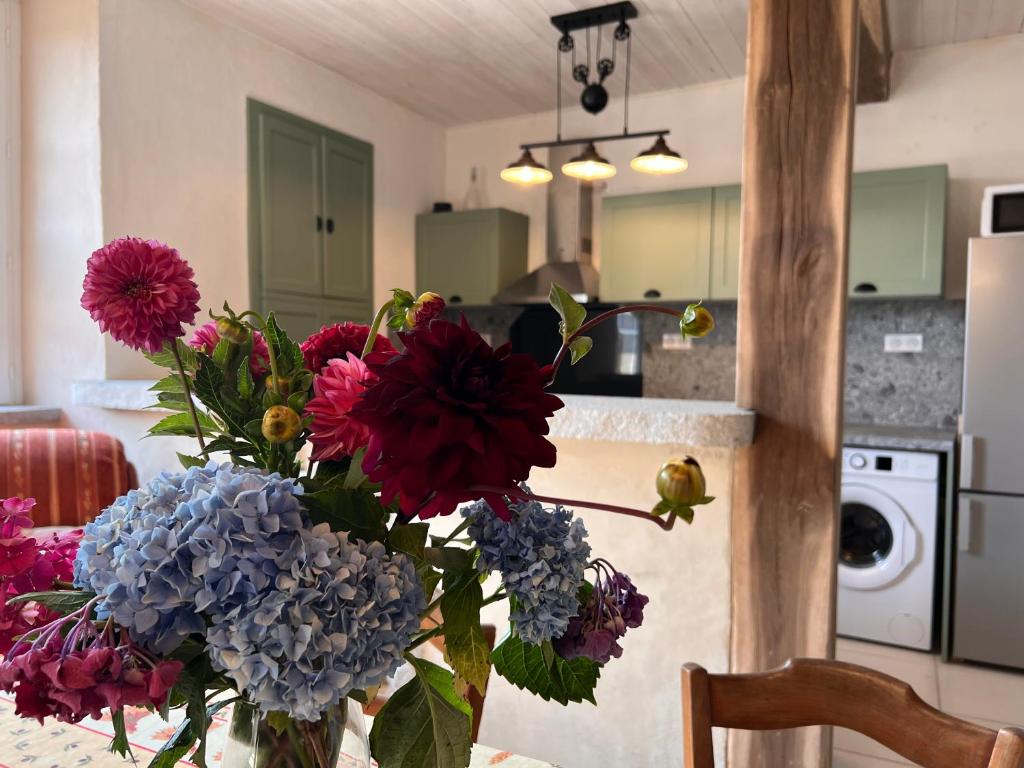 un jarrón de flores sobre una mesa en una cocina en Le Mont de Piegut en Piégut-Pluviers