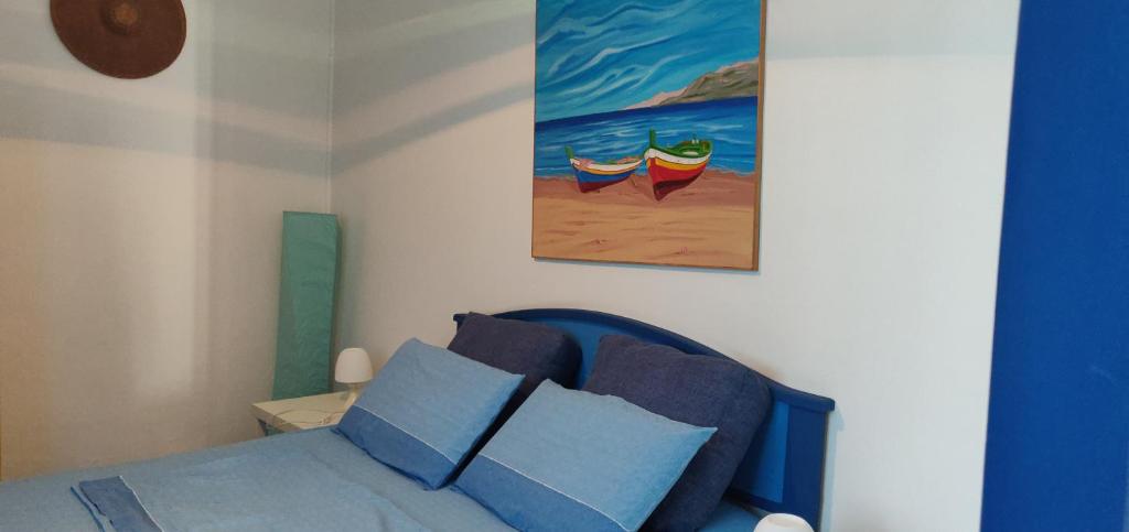 a bedroom with a bed with a painting on the wall at La Casa di Chico in Mondello