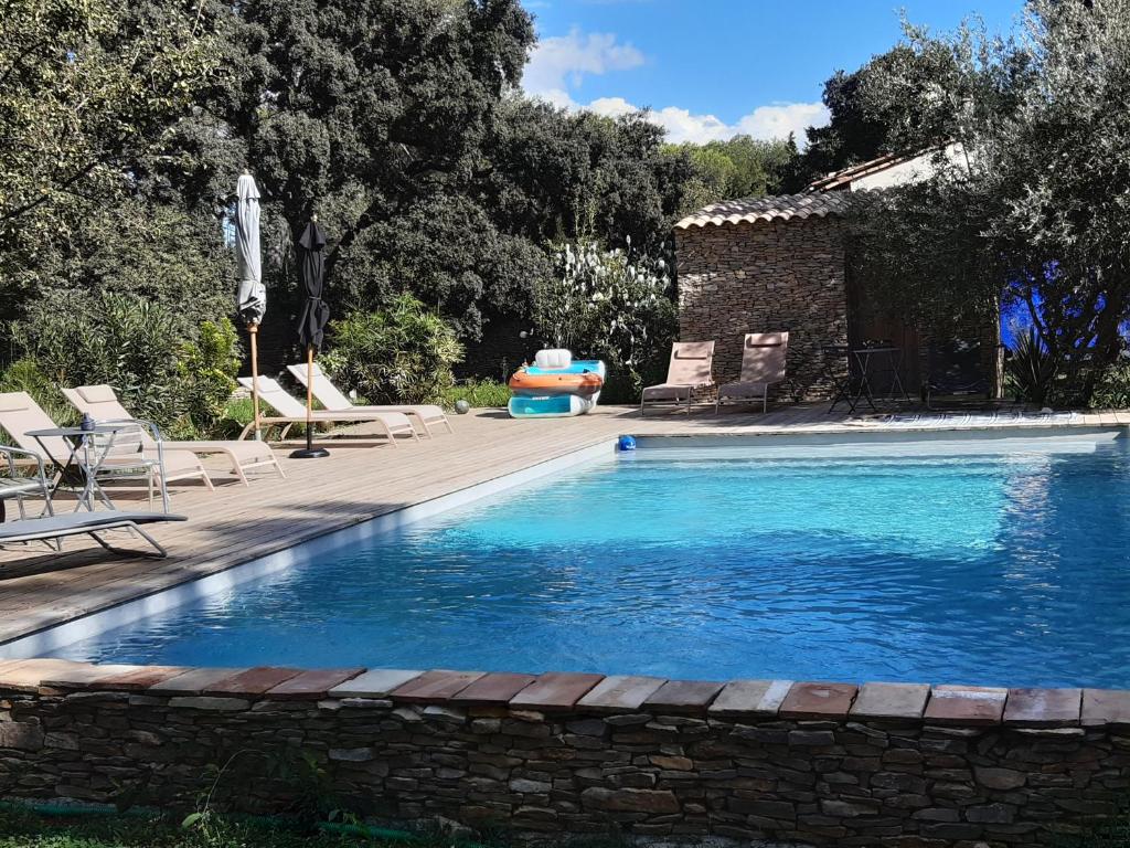 a large swimming pool with chairs and an umbrella at La Finca in Nîmes