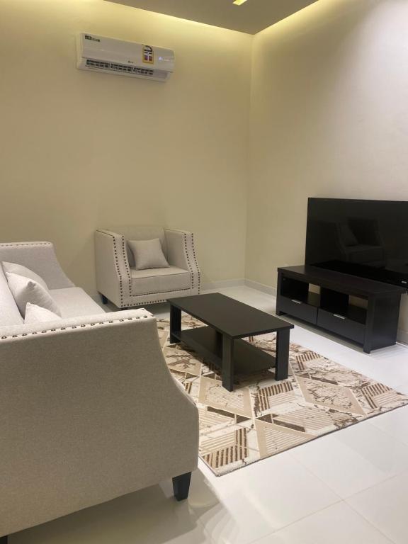 sala de estar con sofá, TV y mesa en Rateel Apartments en Salalah