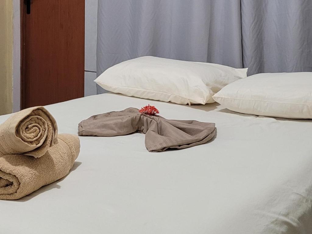 Una cama blanca con toallas y almohadas. en Pousada Primeiro Sol, en João Pessoa