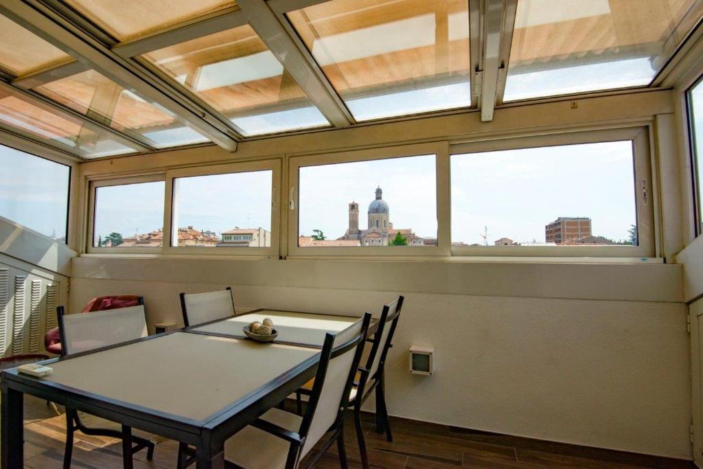 una sala da pranzo con tavolo e alcune finestre di Apartment San Benedetto a Padova