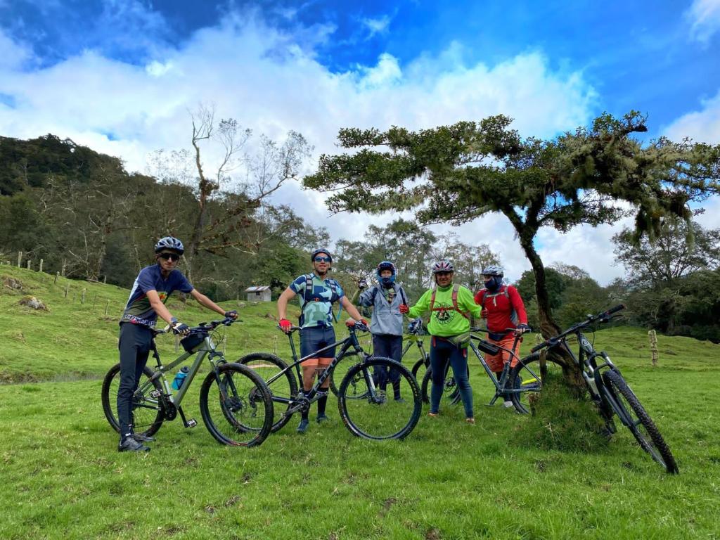 un grupo de personas de pie con bicicletas en un campo en Cabaña Anturios, en San José