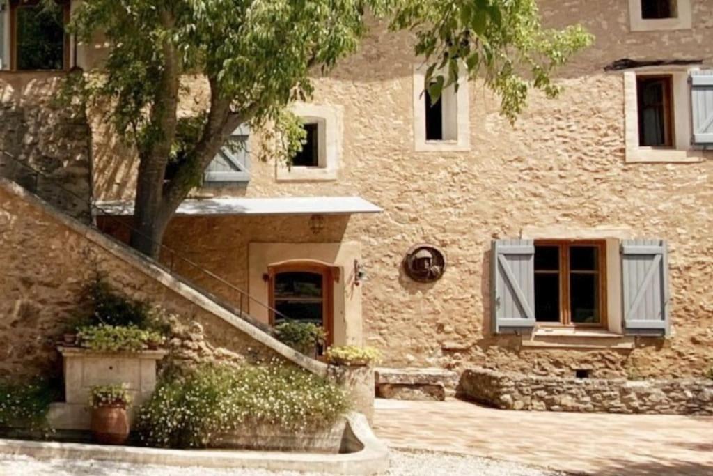 un bâtiment en pierre avec un arbre en face dans l'établissement Campagne du XVII au luxe simple, à Lorgues