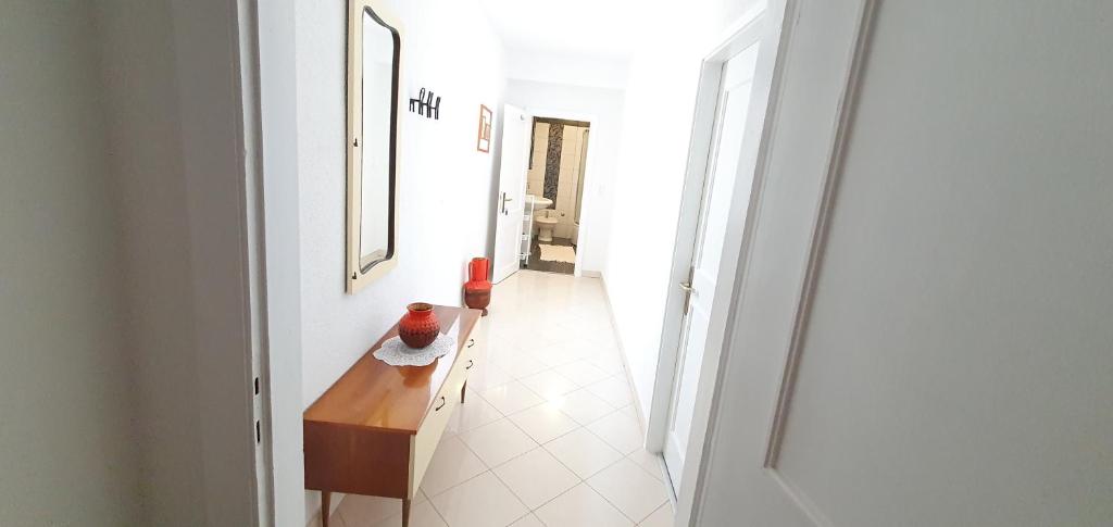 a hallway with a wooden table in a white room at Guesthouse Palma in Mali Lošinj