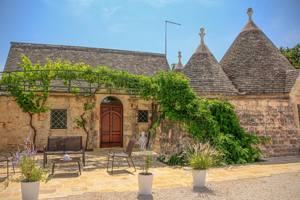 uma casa de pedra com uma porta de madeira e um pátio em TRULLI OLISTICI em Locorotondo