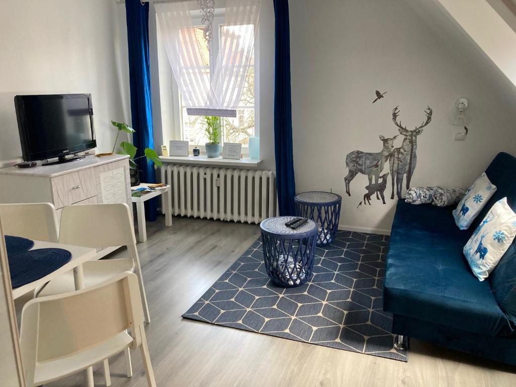 a living room with a blue couch and a tv at Habibi Plac Ratuszowy in Jelenia Góra