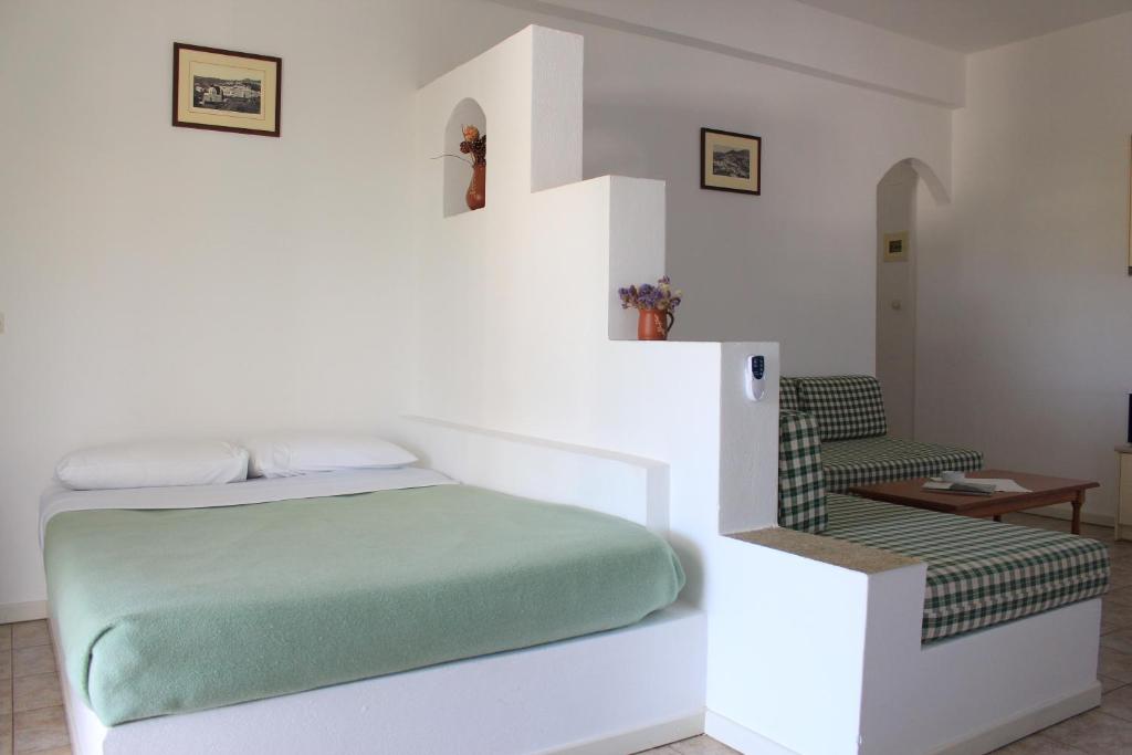 a white bedroom with a bed and a staircase at Eleonas Apartments in Sifnos