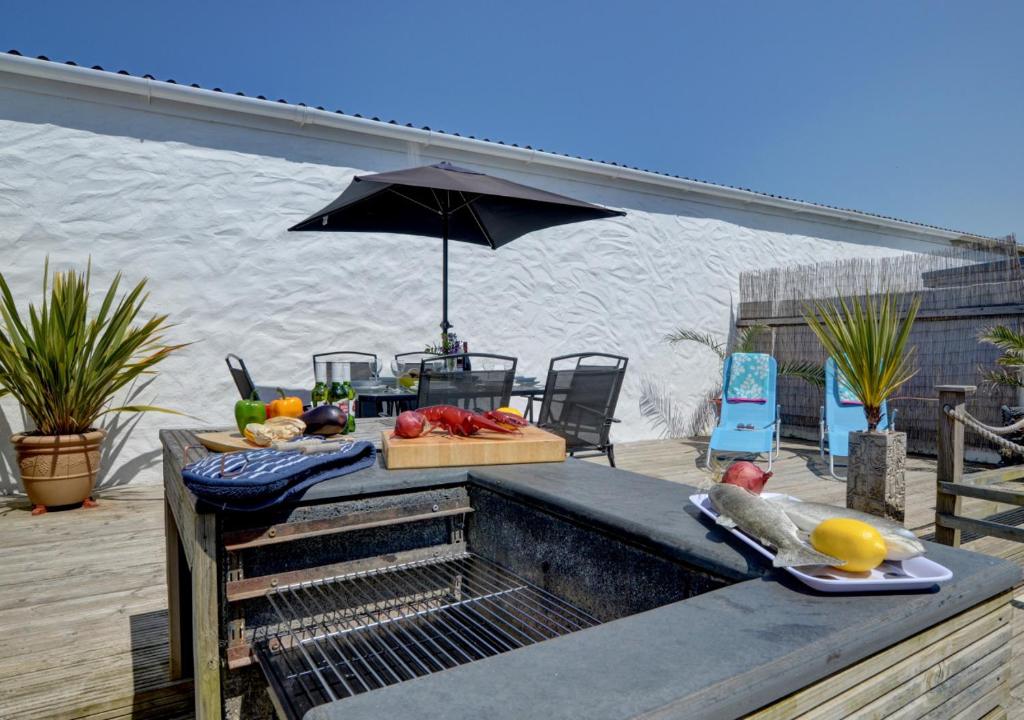 een tafel met fruit en een paraplu op een terras bij Beach Cottage in Croyde