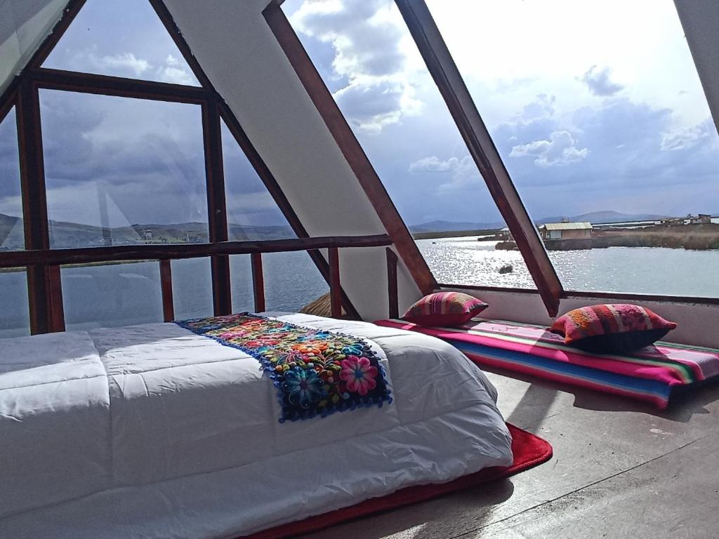 Ce lit se trouve dans un dortoir avec vue sur l'eau. dans l'établissement uros waliski alpina house, à Puno