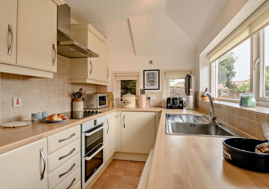 a kitchen with white cabinets and a sink at Skyes House in Southwold