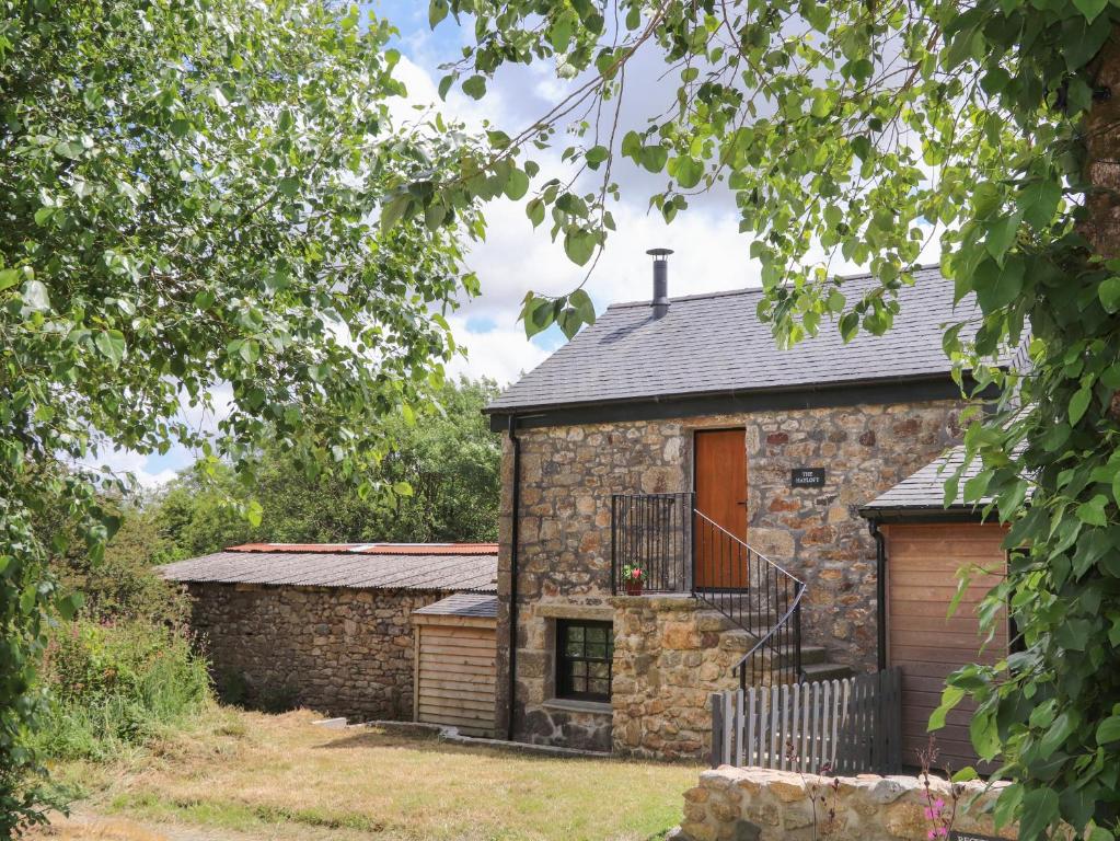 a stone cottage with a wooden door and a balcony at The Hayloft in Helston