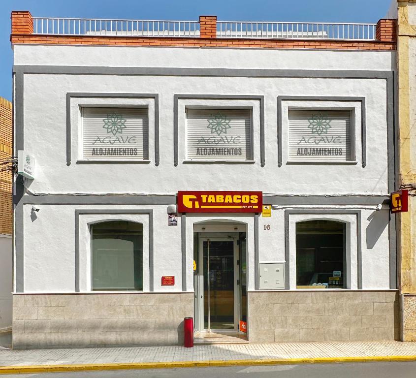 un edificio bianco con un cartello della farmacia di ALOJAMIENTOS AGAVE a Tabernas