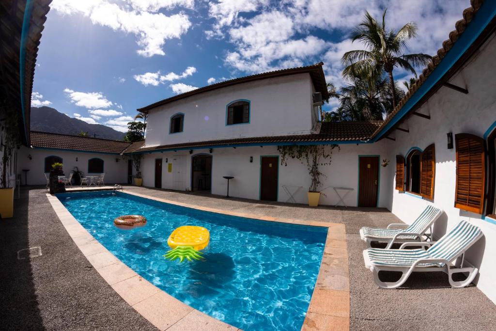 a swimming pool with a pool noodle in front of a house at Villa Salgada Maresias in Maresias