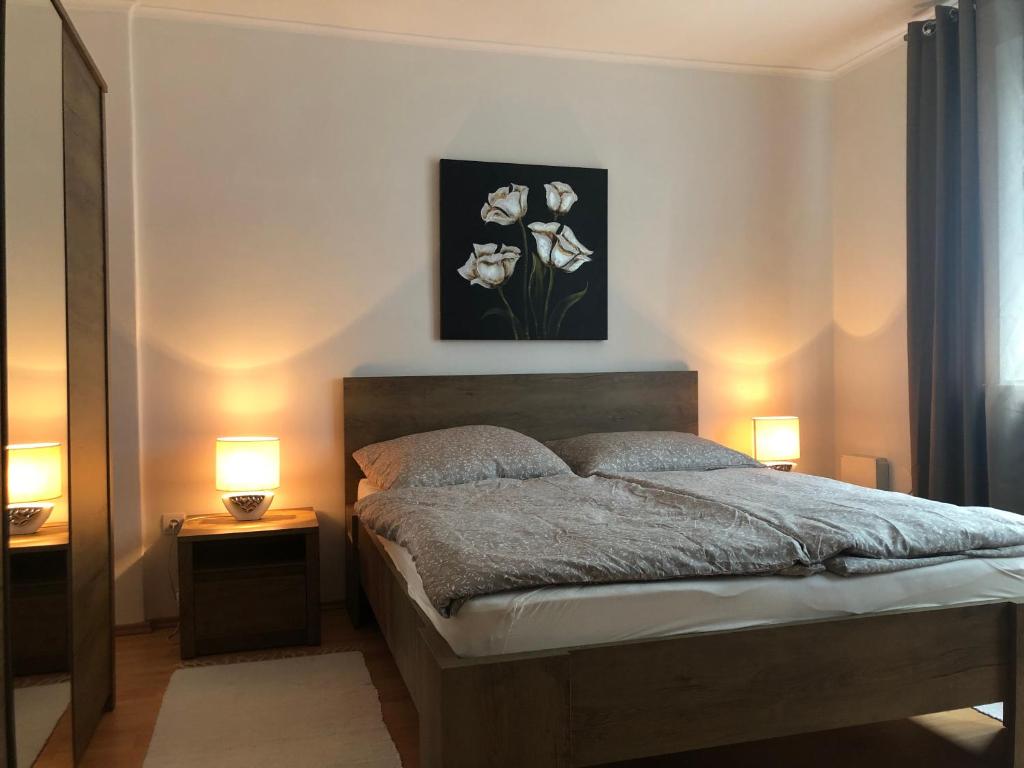 波切尼斯的住宿－Rodinný apartmán Villa Familia，一间卧室配有一张带两盏灯和鲜花的床。