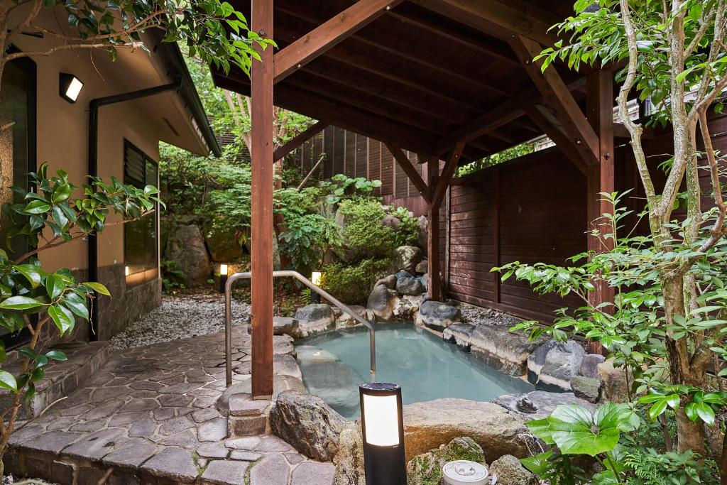 una pequeña piscina en un jardín con una fuente en Ajisai Onsen Ryokan, en Hakone
