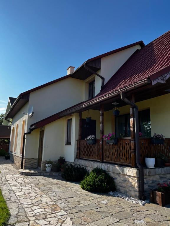 een huis met een veranda en een stenen oprit bij Bieszczadzki Zakątek in Ustrzyki Dolne