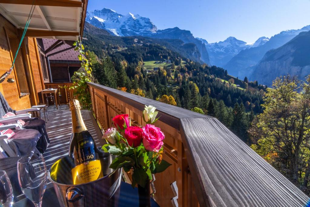 a balcony with a bottle of champagne and flowers at Chalet Aargovia South in Wengen