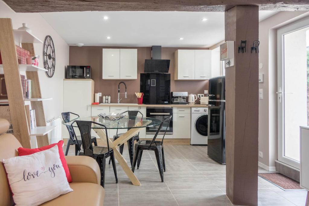 a kitchen and living room with a table and chairs at Le Dionysien *** (petite maison avec terrasse) in Saint-Denis-de lʼHôtel