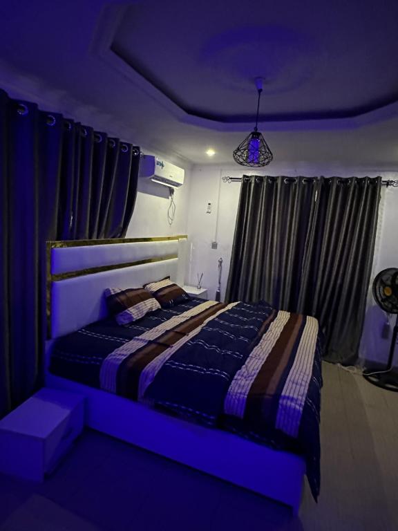 een slaapkamer met een bed in een blauw licht bij 3 Bedrooms Duplex in Ibadan