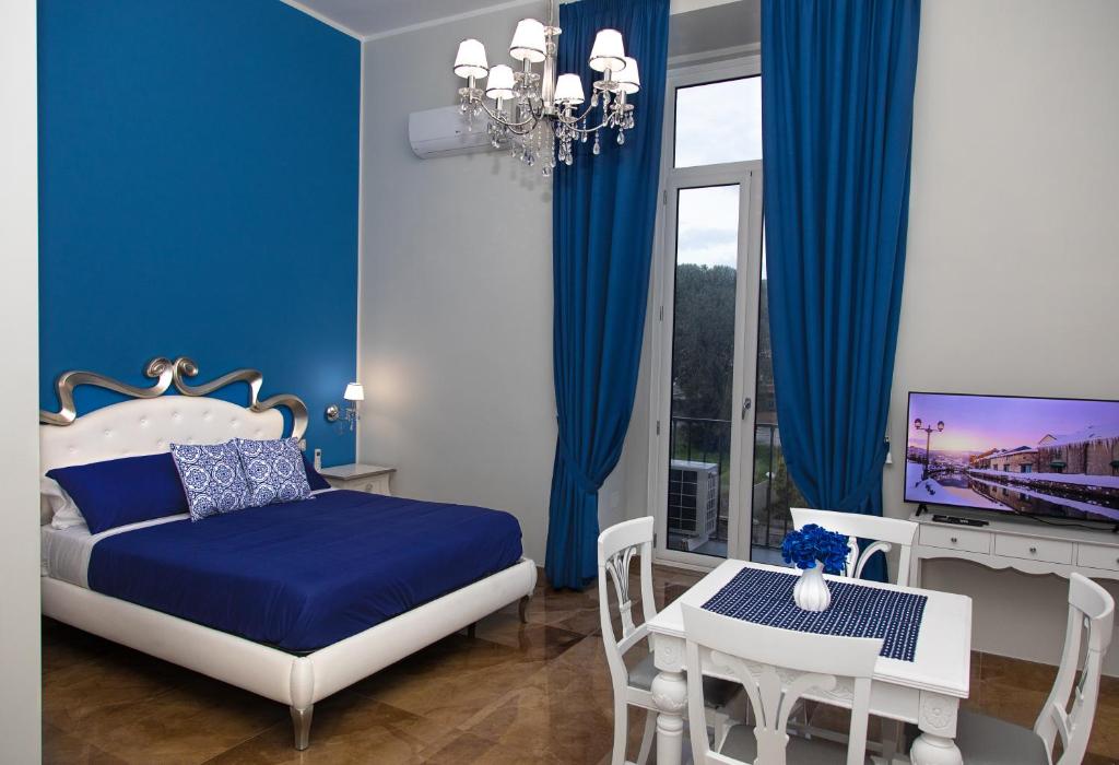 um quarto azul com uma cama, uma mesa e uma televisão em Villa Giuseppina em Nápoles