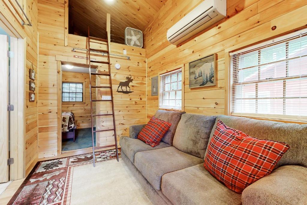 a living room with a couch in a log cabin at Weirs Boulevard Dreamin' in Laconia
