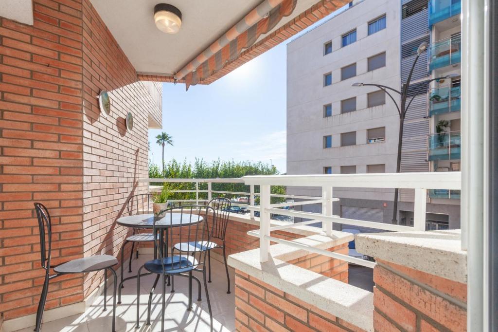 a balcony with tables and chairs on a brick wall at Fantástico apartamento en la playa. A/A y vistas in Pineda de Mar