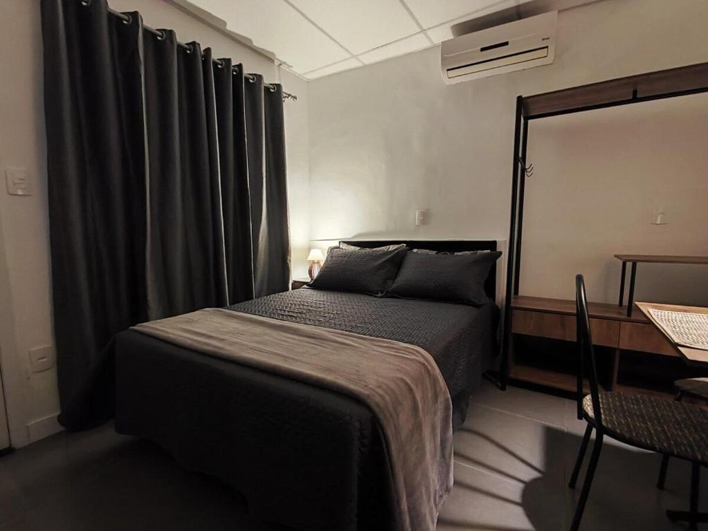 um quarto com uma cama, uma secretária e um espelho em VILLA BILAC 10 - Studio próximo à Vila Germânica Bairro da Velha em Blumenau