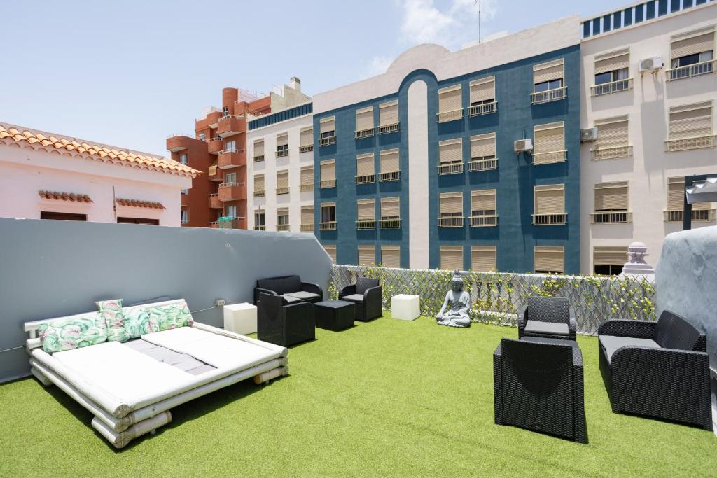 a rooftop patio with a couch and chairs on the grass at Wanderlust Hostel in Santa Cruz de Tenerife