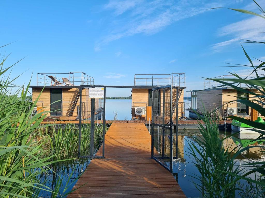 a wooden walkway leading to a house on the water at SunRise HouseBoats in Łazy
