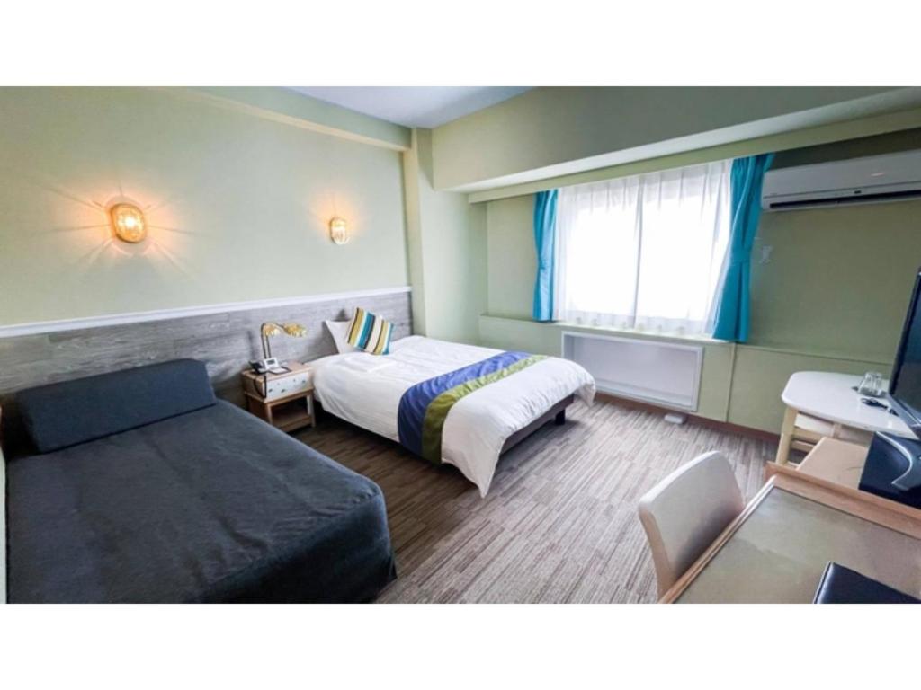 Hotel AreaOne Sakaiminato Marina - Vacation STAY 81682v في ساكايميناتو: غرفه فندقيه بسرير واريكه