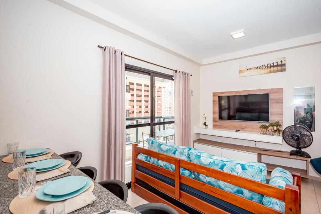- un salon avec une table, un canapé et une télévision dans l'établissement Flat Top - 100 M Da Praia De Pitangueiras 4083, à Guarujá