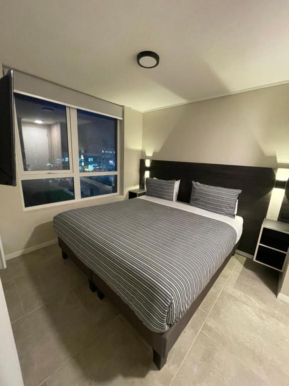 una camera con un grande letto e una finestra di Epicentro Suites Apart Hotel - Valdivia a Valdivia