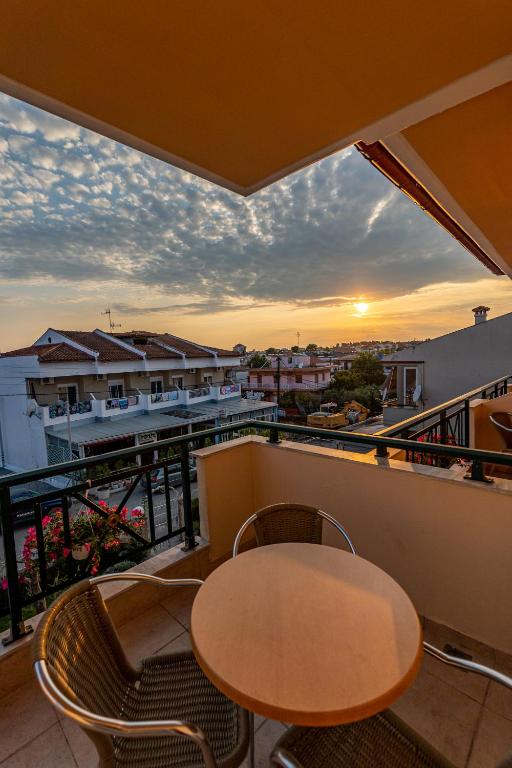 a balcony with a table and chairs and a sunset at Thalassa Apartments in Kallithea Halkidikis