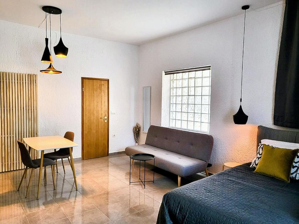 ein Schlafzimmer mit einem Bett, einem Tisch und einem Sofa in der Unterkunft studio Square Funtana in Funtana