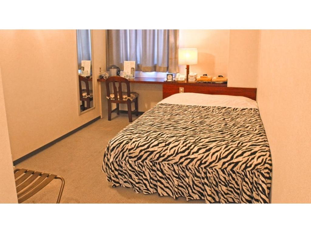 Business hotel Green Plaza - Vacation STAY 43964v في Chikuma: غرفة في الفندق مع سرير ومكتب