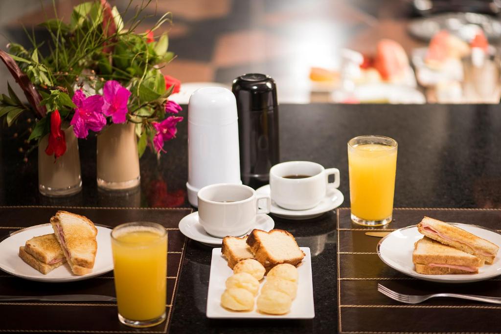 - une table avec des assiettes de pain grillé et 2 tasses de jus d'orange dans l'établissement STATUS Motel, à Belo Horizonte