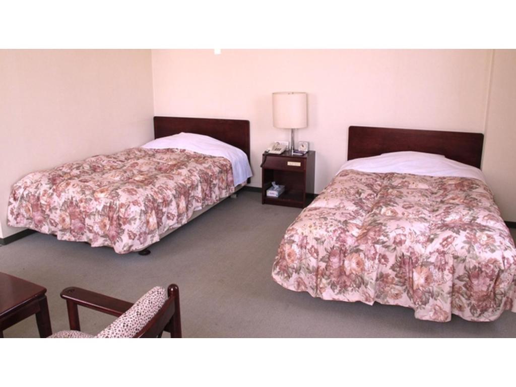 um quarto com 2 camas, uma mesa e uma cadeira em Business hotel Green Plaza - Vacation STAY 43971v em Chikuma