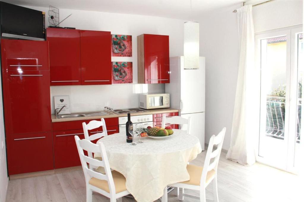 une cuisine avec des placards rouges, une table et des chaises dans l'établissement Sea view and beach apartament Green, Petar House, à Vodice