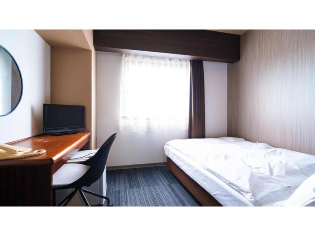 a bedroom with a bed and a desk and a computer at Hotel AreaOne Minamisoma - Vacation STAY 56244v in Minamisouma
