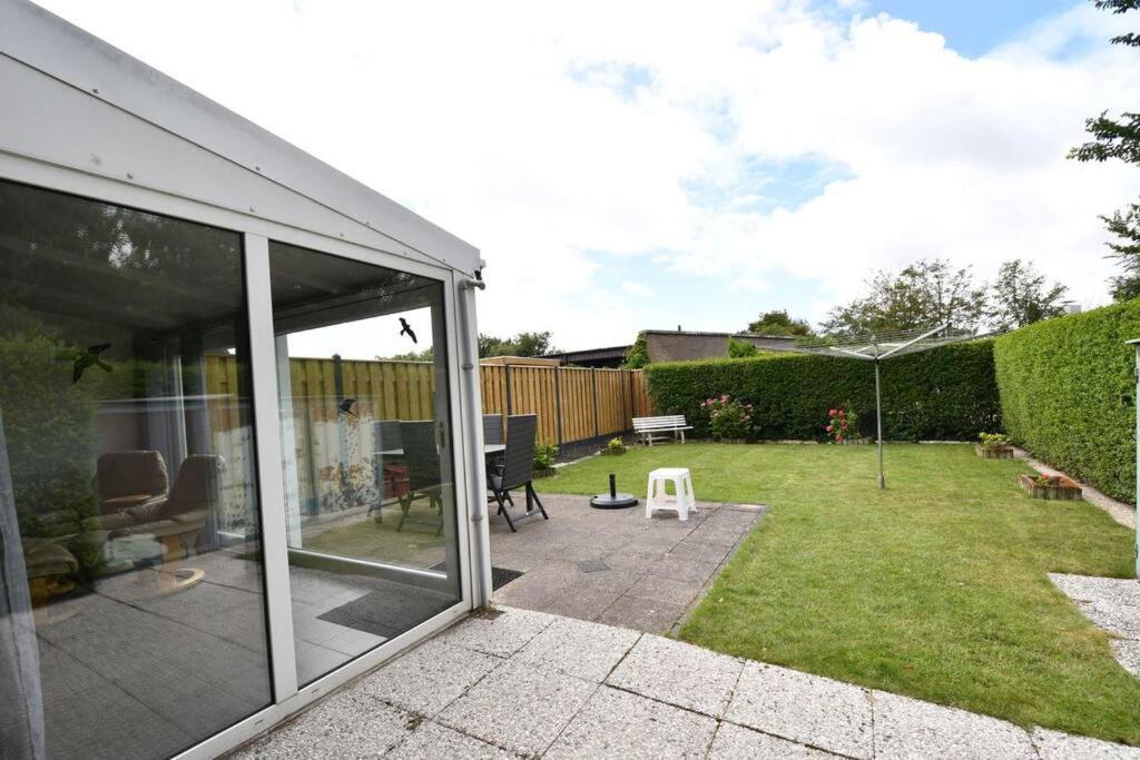 a garden with a sliding glass door and a patio at Houtenburgseweg 2 in Zoutelande
