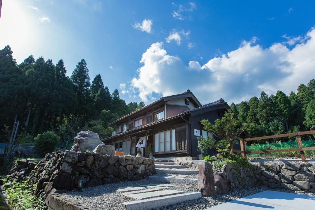uma casa nas montanhas com uma parede de pedra em Whole house rental inn Umu - Vacation STAY 60715v em Maibara