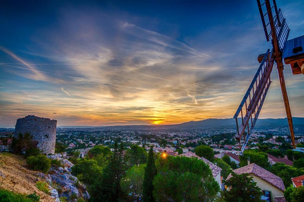 een uitzicht op de stad bij zonsondergang met een kraan bij Au charme provençal in Allauch