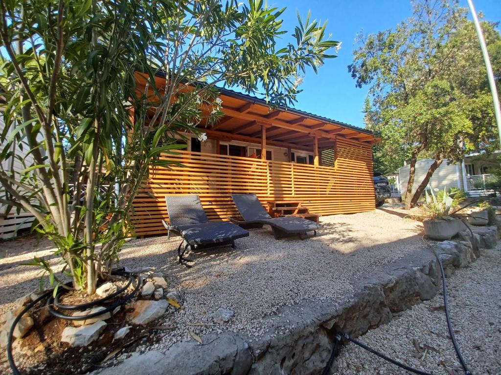 um chalé de madeira com duas cadeiras e uma mesa em Camping Park Soline - Rose PB -Mobile Home em Biograd na Moru