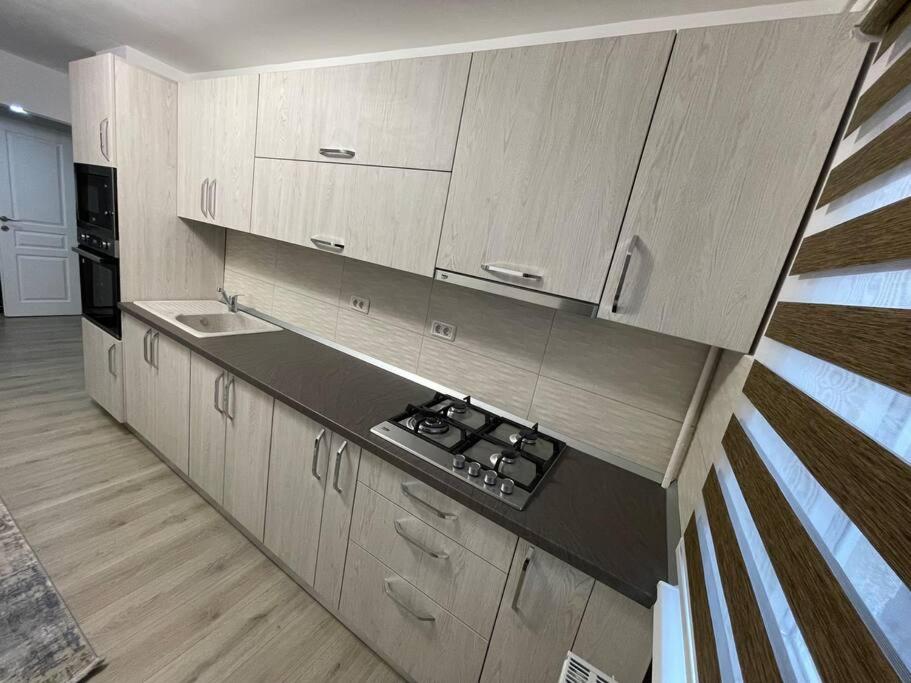 a kitchen with white cabinets and a black counter top at Apartament regim hotelier in Caransebeş