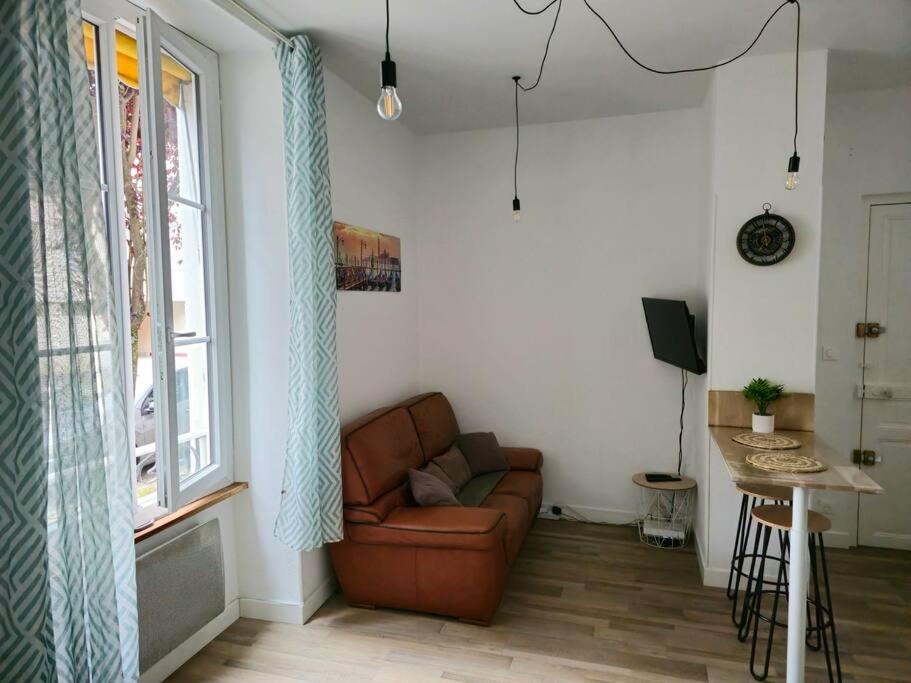 uma sala de estar com um sofá e uma janela em Le Verdun - centre Pau - calme em Pau