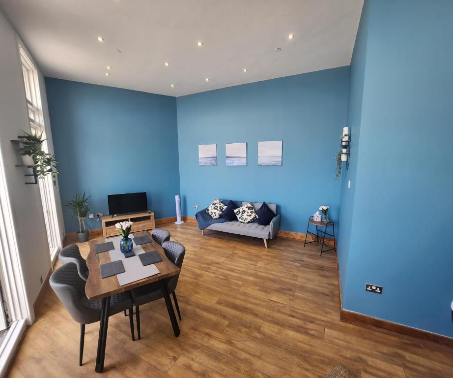 Kent的住宿－Imperial Suites Heart Of Margate! sleeps 6，客厅拥有蓝色的墙壁、桌子和沙发