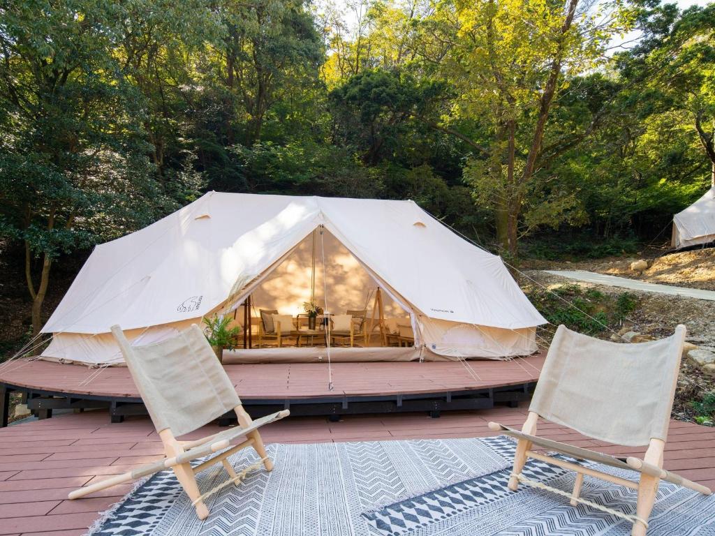 ein großes weißes Zelt mit zwei Stühlen auf einer Terrasse in der Unterkunft Nordisk Hygge Circles Ugakei - Vacation STAY 75323v in Komono