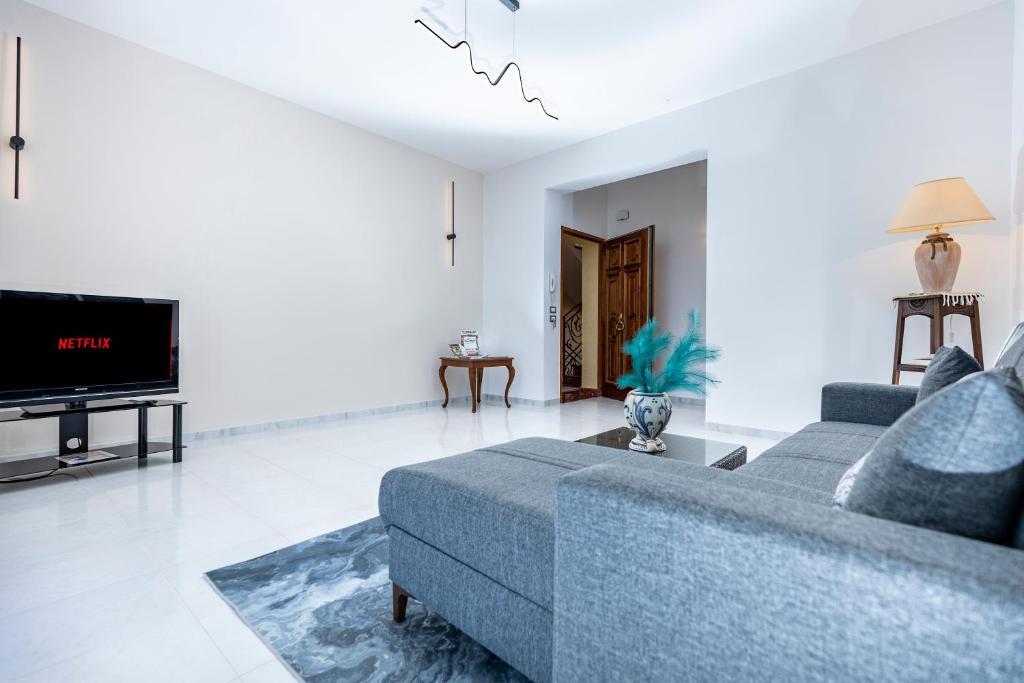 un soggiorno con un divano blu e una TV di Casa vacanza lido a Sciacca